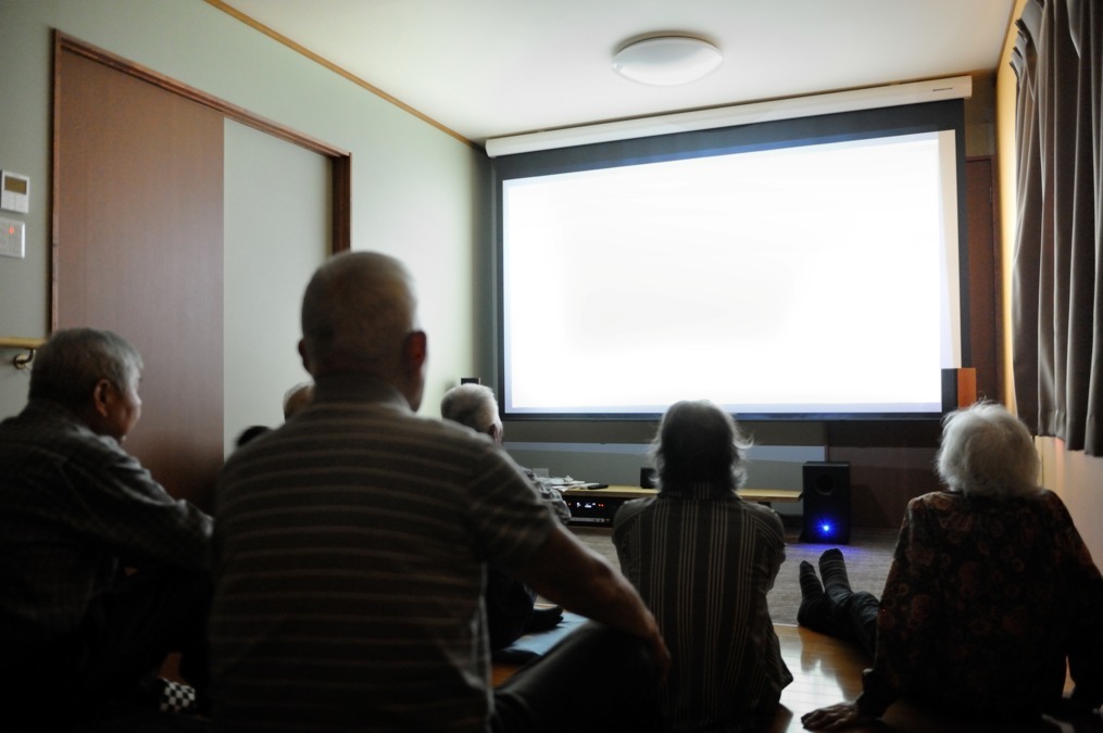 笑楽日の写真9枚目：大スクリーンで映画や、外出した際の写真などを見て回想法につなげます。