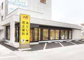 ありしま矯正歯科の写真:黄色い看板が目印の白い建物です。