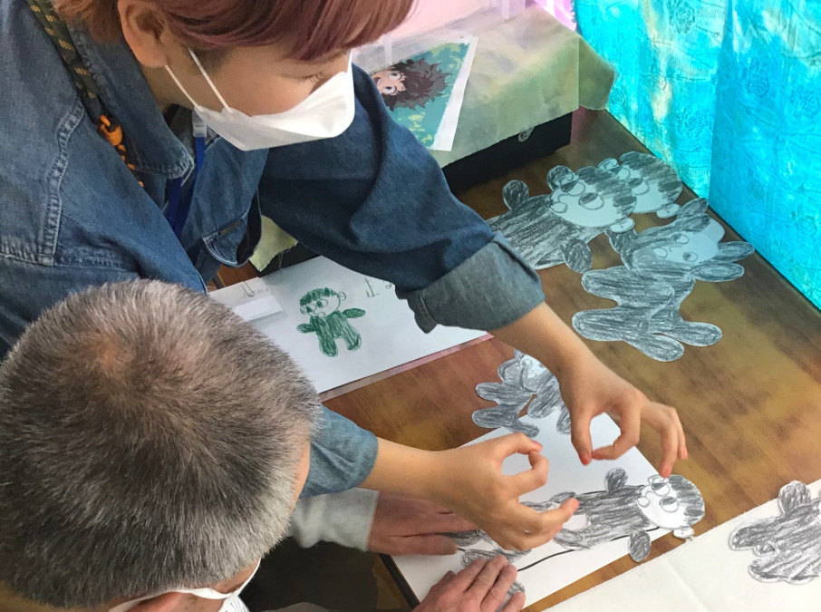 FAN（生活支援員の求人）の写真3枚目：商品製作の１コマ。できあがったイラストの印刷位置を利用者さんと決めています。