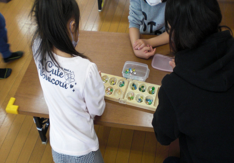 八日市北こどもの家学童保育所の写真4枚目：学童支援員と一緒にマンカラ勝負