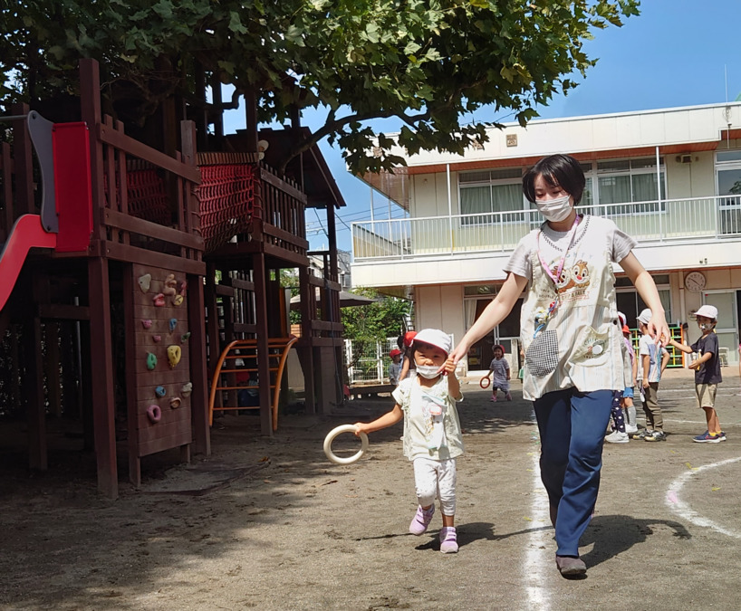 彰栄幼稚園の写真7枚目：年長児と同じことをしたい年少さんは、年長担任と一緒に走りました。リレーごっこ。