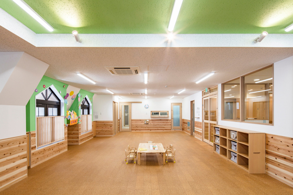 風の保育園（一般事務/管理部門の求人）の写真3枚目：保育室はコルクで全面床暖房。奥に厨房の小窓が見えます。