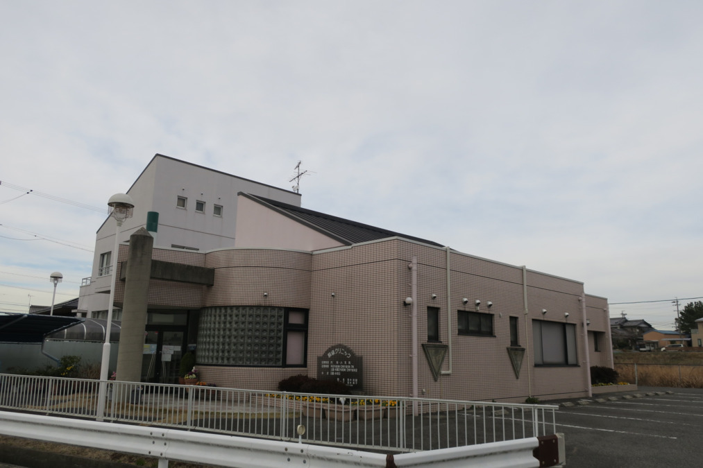 駒場クリニック（医療事務/受付の求人）の写真2枚目：田んぼの中に立つピンクの建物