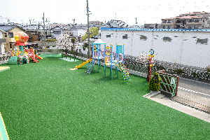 さくらヶ丘保育園の写真2枚目：全面人工芝の広い園庭と大きな複合遊具で戸外遊びを十分楽しめます！