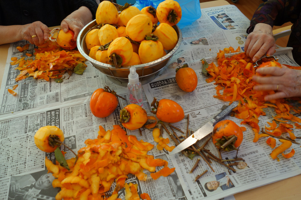 いやしの里ハナモト（介護職/ヘルパーの求人）の写真4枚目：干し柿づくりです。皮むきはおちゃのこさいさい。