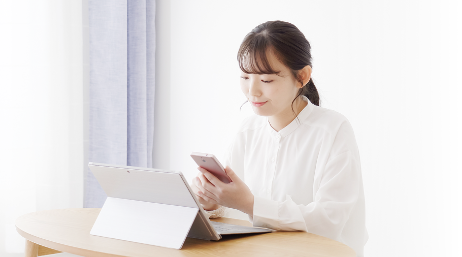 女性が自宅でスマートフォンやパソコンを使い、ジョブメドレーで仕事探しをしている様子。